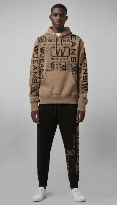 חליפת טרנינג מבית W JEANS הכוללת קפוצ'ון בצבע שקד, ומכנס שחור עם הדפסי לוגו בולטים בשחור, בעיצוב אורבני ייחודי.